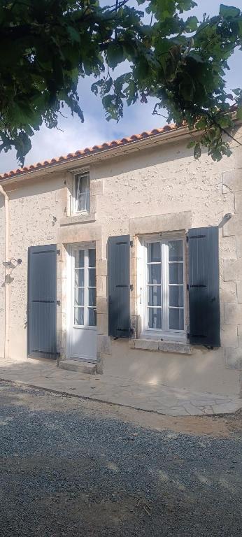 un bâtiment blanc avec deux fenêtres et des portes bleues dans l'établissement Chambre,piscine,petit déjeuner inclus, à Chantonnay