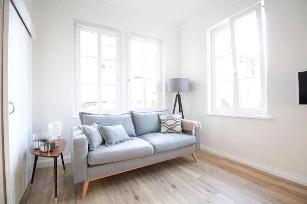 a living room with a couch and two windows at Boutique Charme Apartment in Baden-Baden