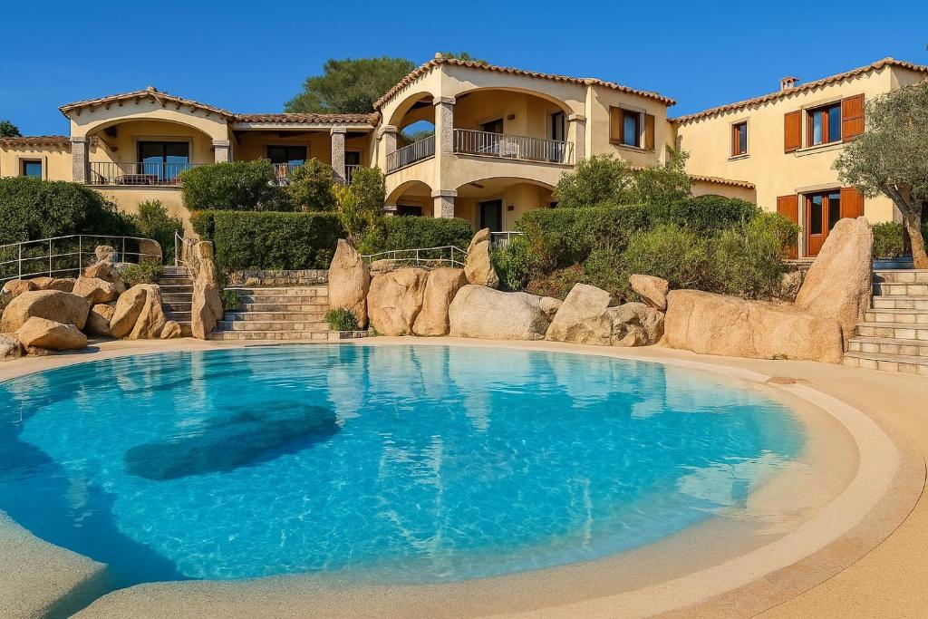a large blue swimming pool in front of a house at Wind Rose Exclusive -Natural pool 50 m from the Sea in Olbia