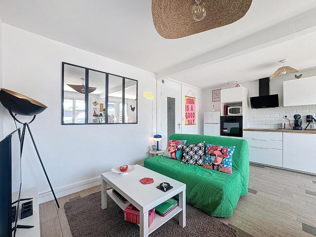 un salon avec un canapé vert et une table dans l'établissement Maison colorée - 2 chambres - À 5 min de la mer, à Plérin