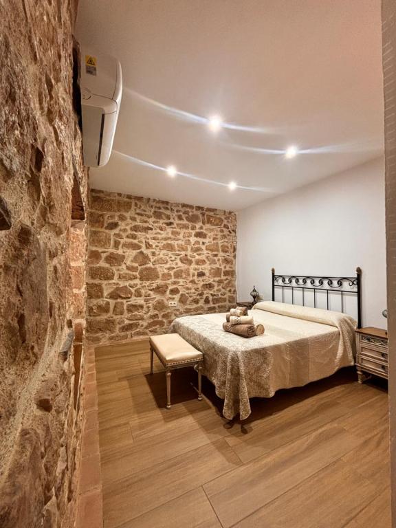 sypialnia z łóżkiem i kamienną ścianą w obiekcie La casa del castillo w mieście Baños de la Encina