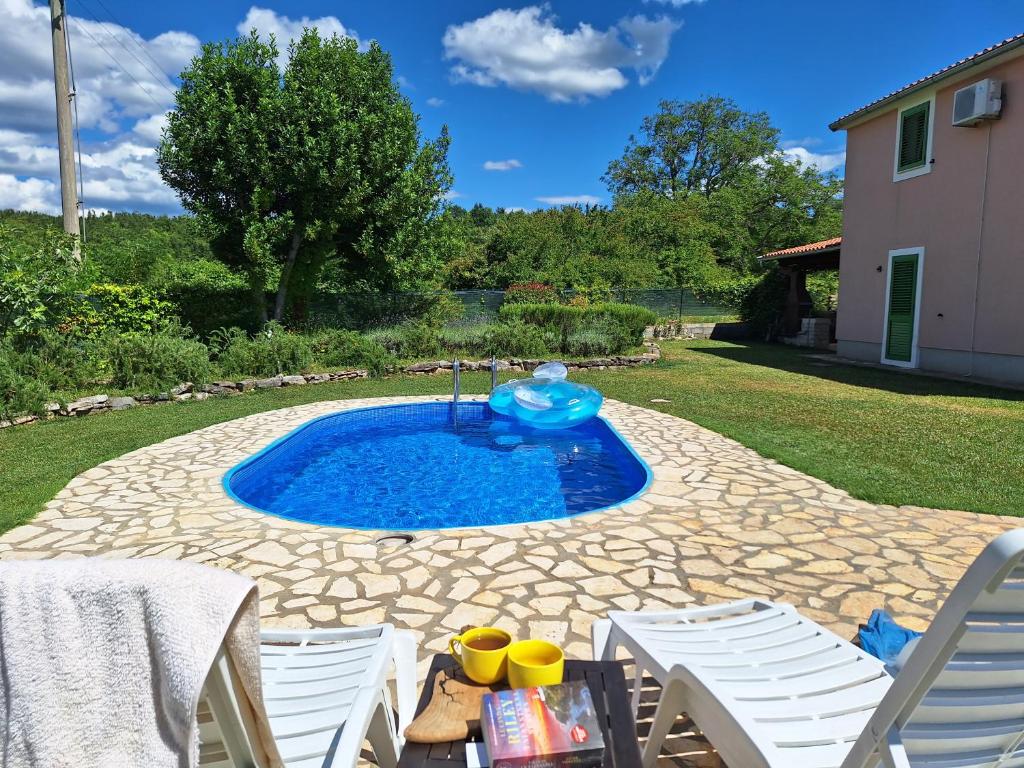 a swimming pool with two chairs and a table at Villa Malini in Grožnjan