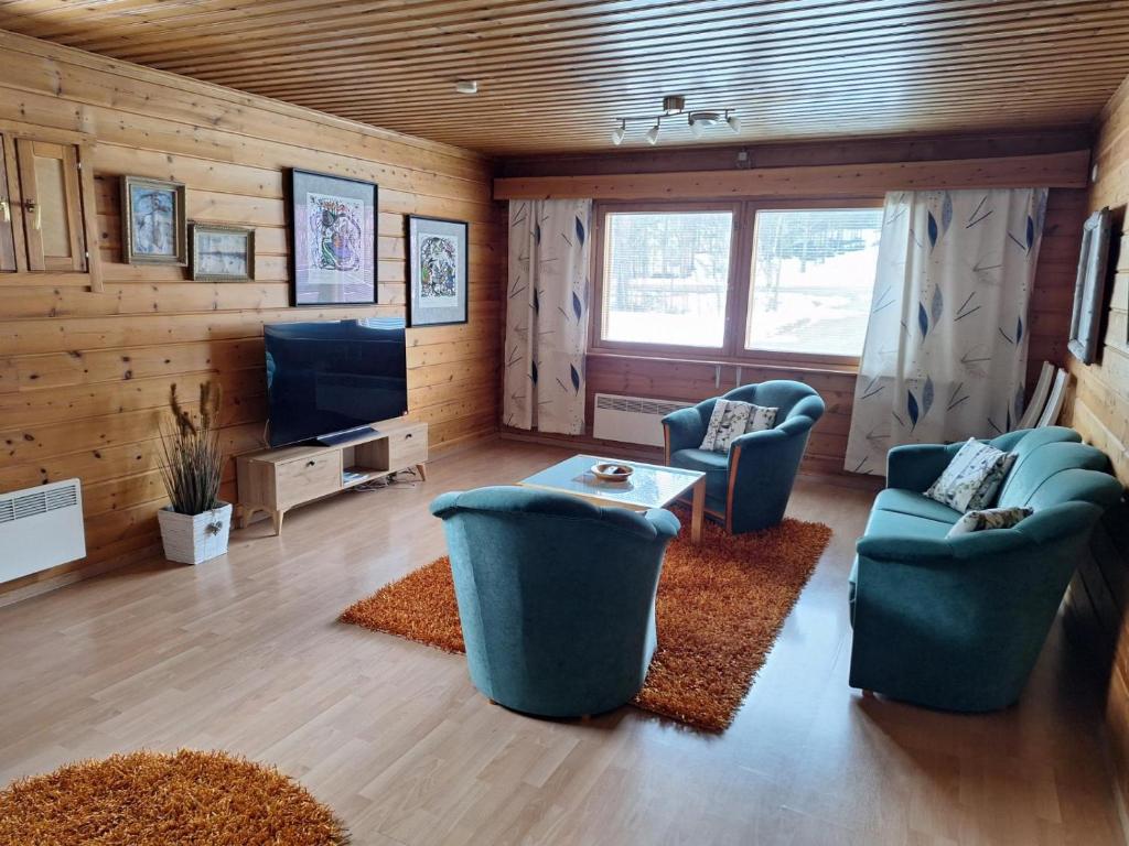 un soggiorno con 2 sedie blu e una TV di Rauhan pesä a Karigasniemi