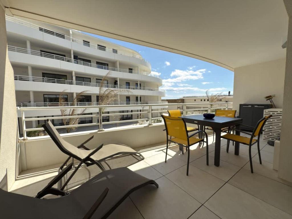 un balcon avec une table et des chaises et une grande fenêtre dans l'établissement Valras-Loc Archipel Panarea Appartement climatise, à Valras-Plage