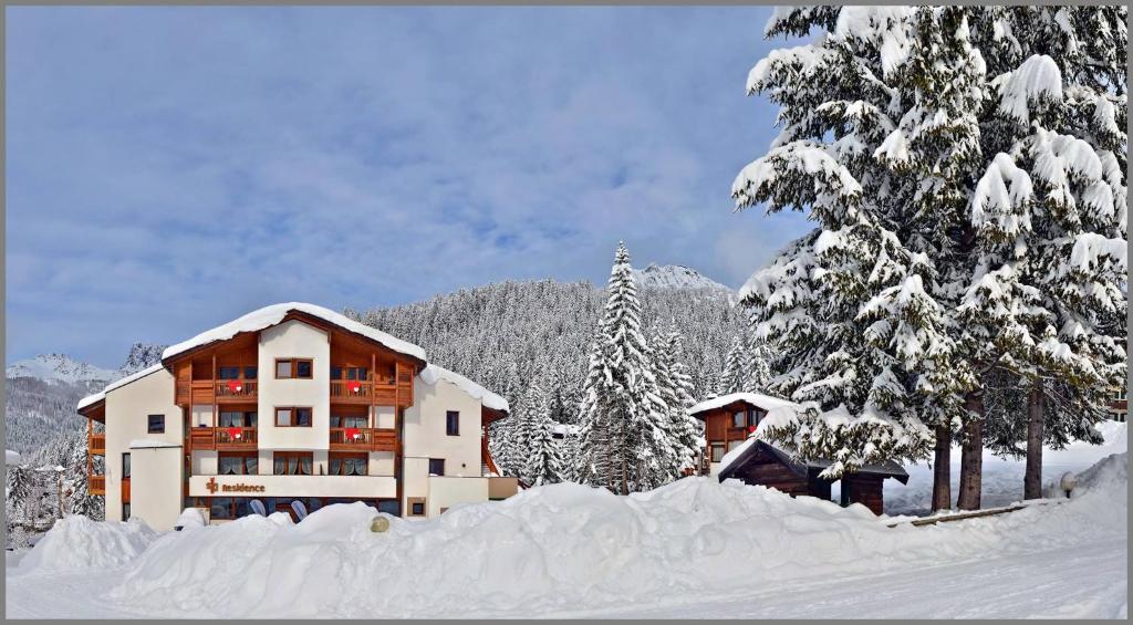 un edificio coperto di neve di fronte agli alberi di Ski Residence a San Martino di Castrozza