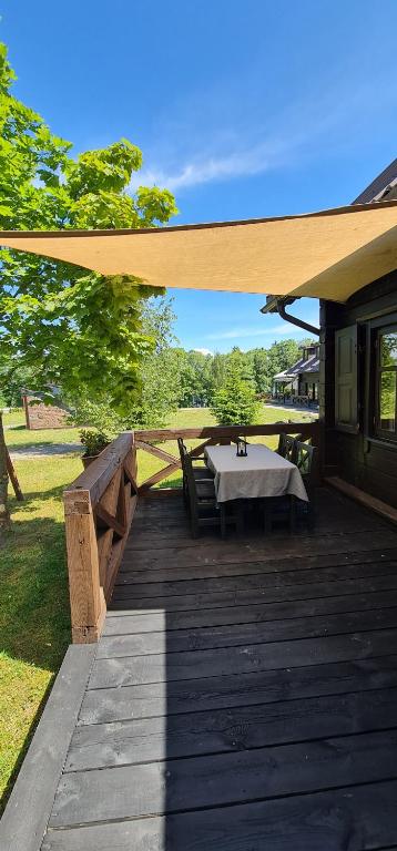 a wooden deck with a table on a house at Asvejos sodyba in Skirlėnai