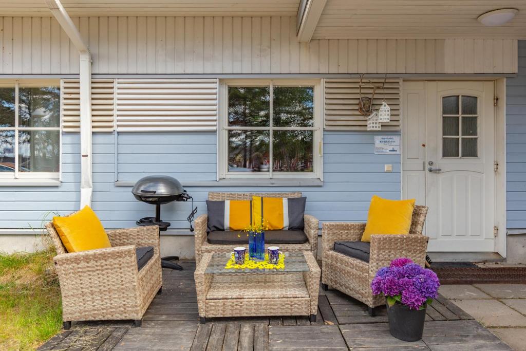 a patio with wicker chairs and a table with yellow pillows at Kuukkeli Saariselkä Inn in Saariselka