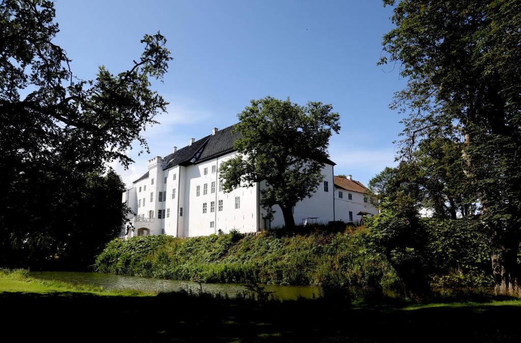a large white building next to a river at Dragsholm Slot in Hørve