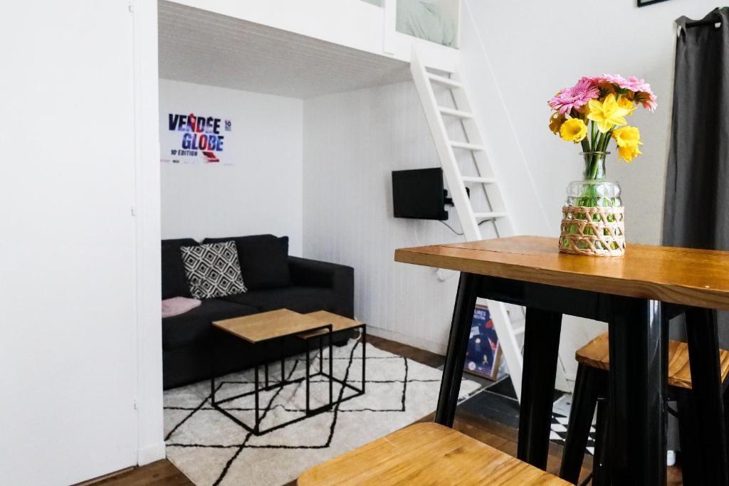 - un salon avec un canapé et une table ornée d'un vase de fleurs dans l'établissement Studio cœur de ville - 2 personnes, à Les Sables-dʼOlonne