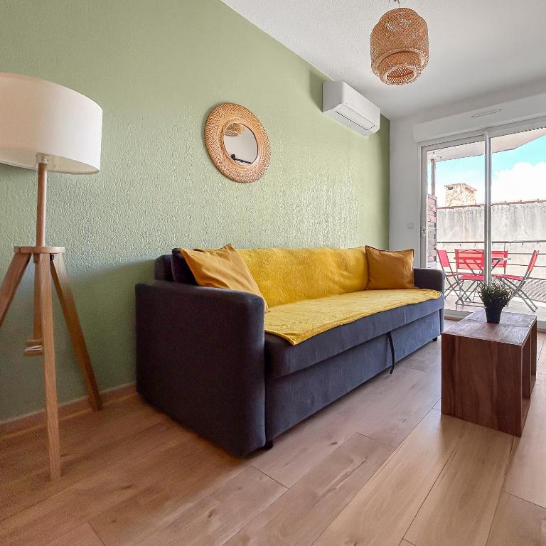 - un salon avec un canapé bleu et une couverture jaune dans l'établissement T2 cosy avec terrasse & parking à 2 pas du port, à La Ciotat