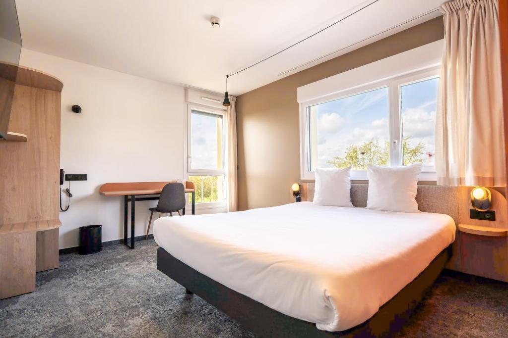 a hotel room with a bed and a desk and a window at Hôtel AKENA Chalons-en-Champagne in Châlons-en-Champagne