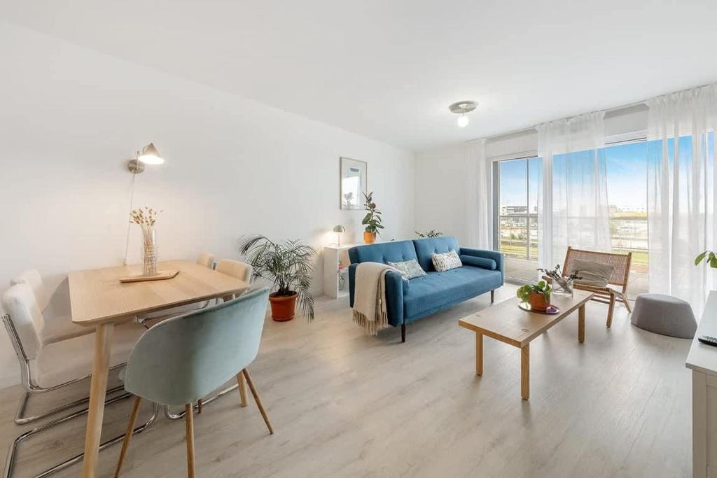 un salon avec un canapé bleu et une table dans l'établissement L'Odyssée - Bel appartement -Terrasse/Parking, à Vannes