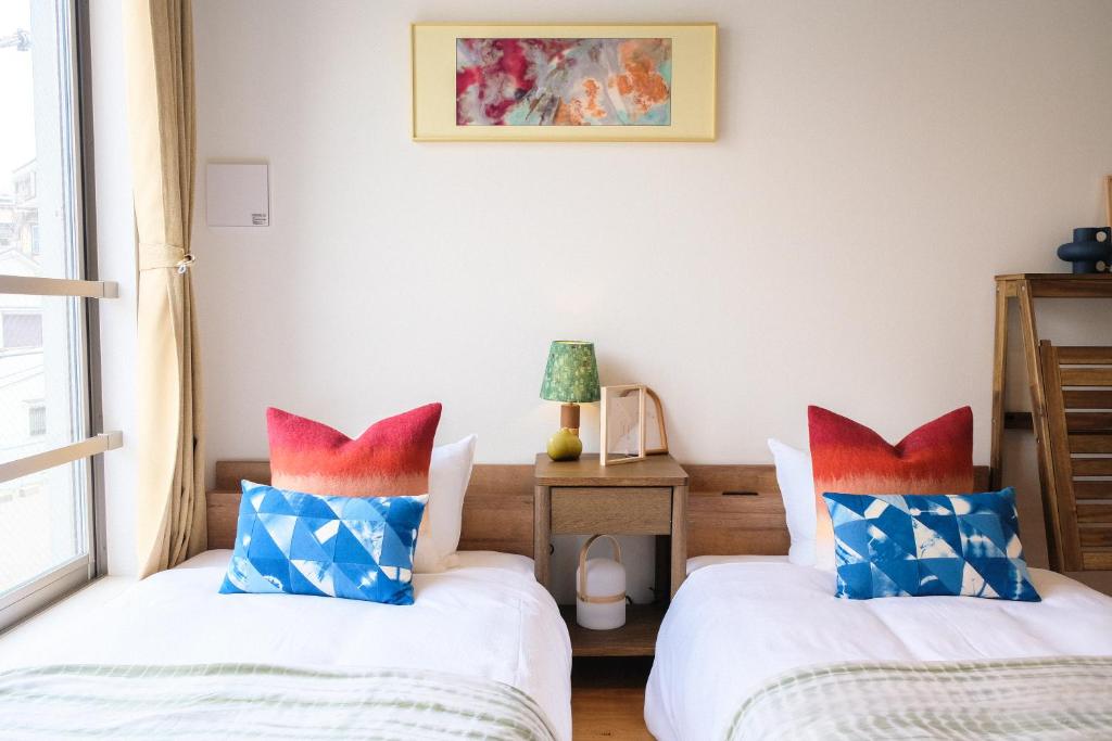 a bedroom with two beds with blue and red pillows at Mi-Hotel MIYA Shinjuku 新宿四谷 in Tokyo