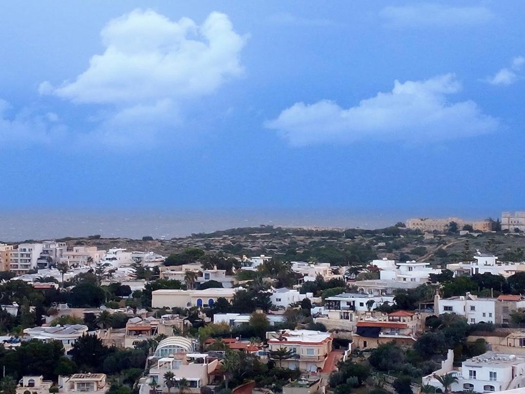 a city with white buildings and a blue sky at Comfortable vacation home with great views in Mellieħa