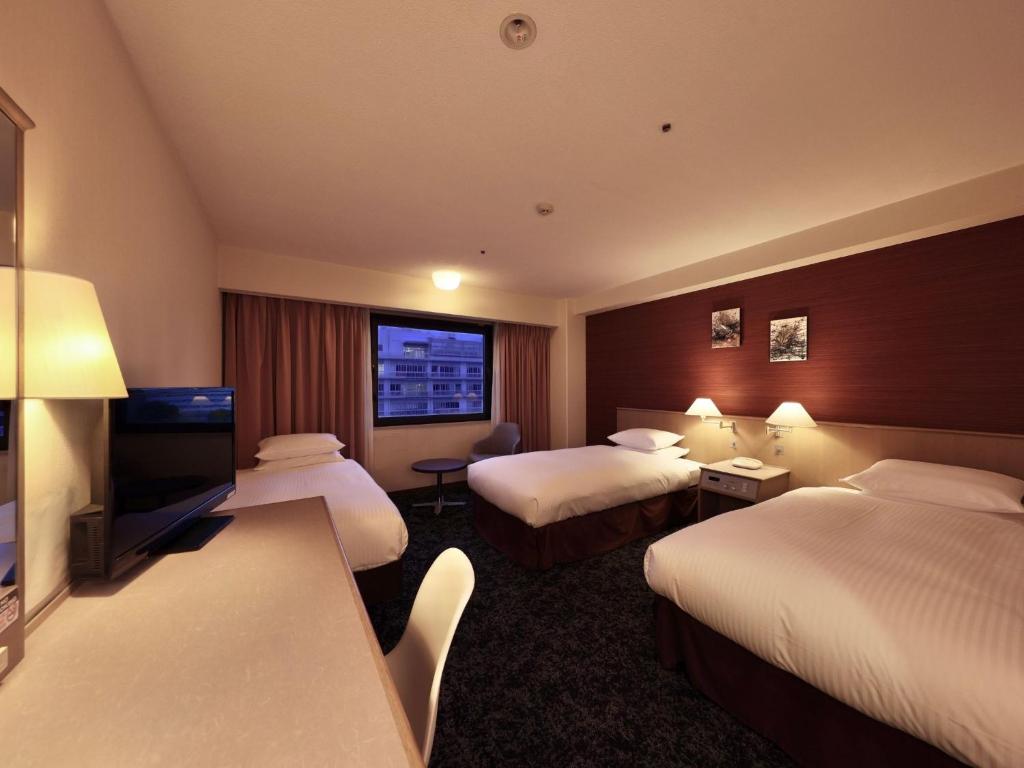 a hotel room with two beds and a flat screen tv at Minamisenri Crystal Hotel - Vacation STAY 78162v in Suita