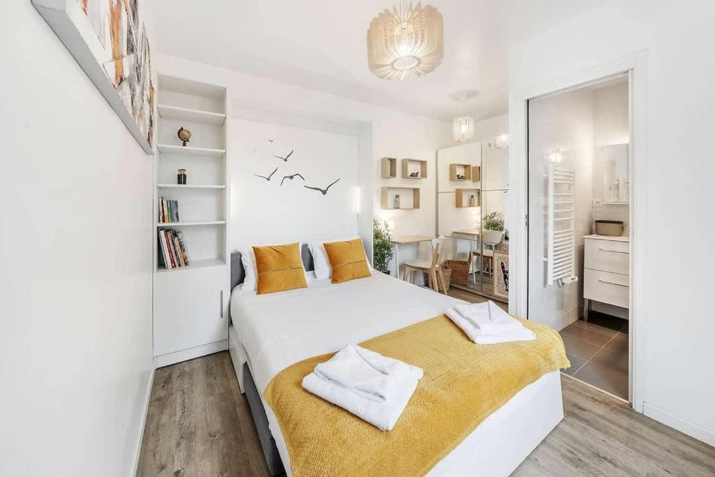 - une chambre blanche avec un grand lit blanc et des oreillers orange dans l'établissement L'Annexe - Plage 50 m et Remparts à 500 m, à Saint-Malo