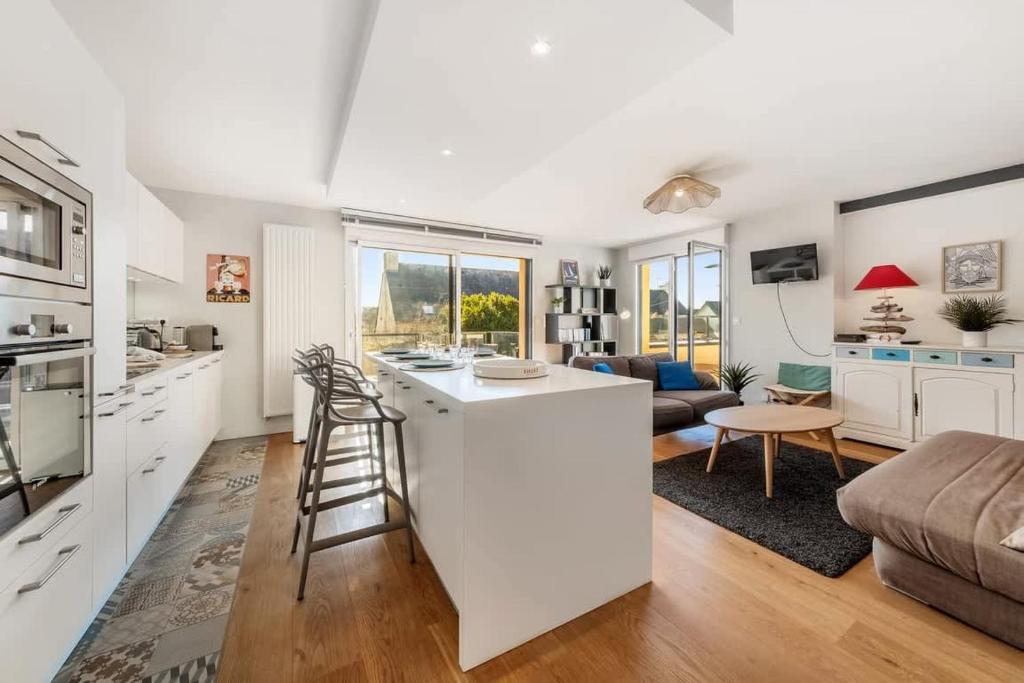 Il comprend une cuisine et un salon avec un bar et un canapé. dans l'établissement La Marinière - Terrasse et parking, proche plage, à Saint-Malo