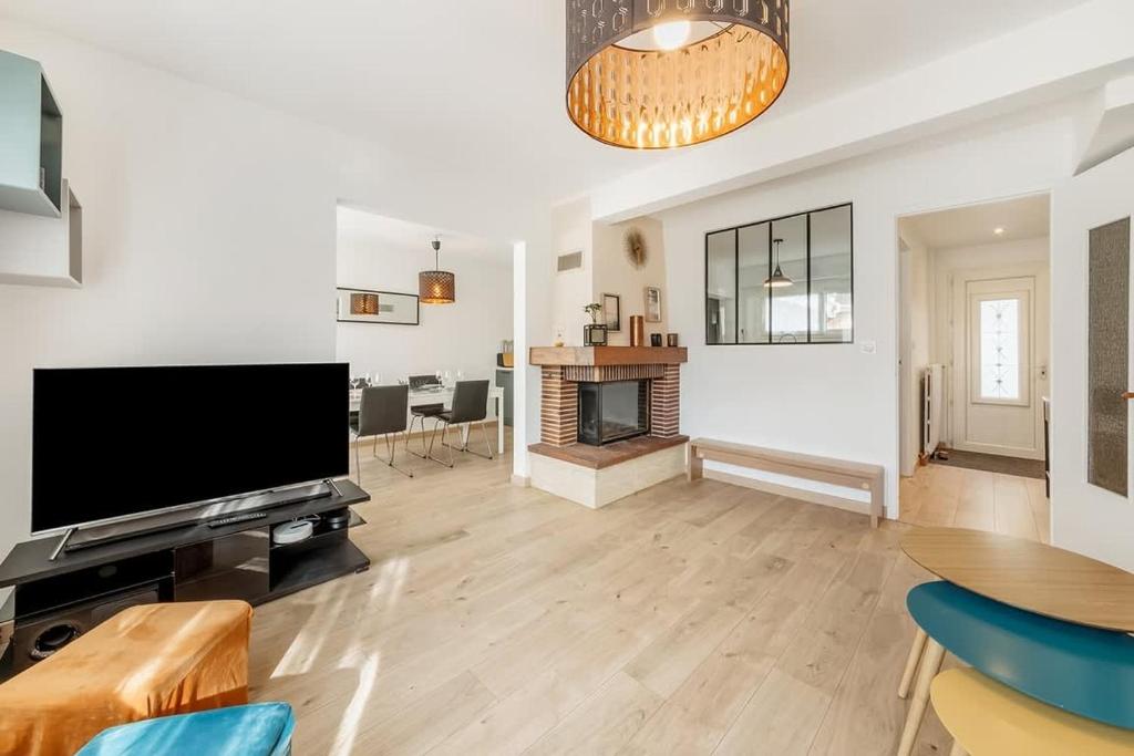 un salon avec une télévision et une cheminée dans l'établissement La Maison Mariotte, 3 chambres, parking extérieur, à Rennes