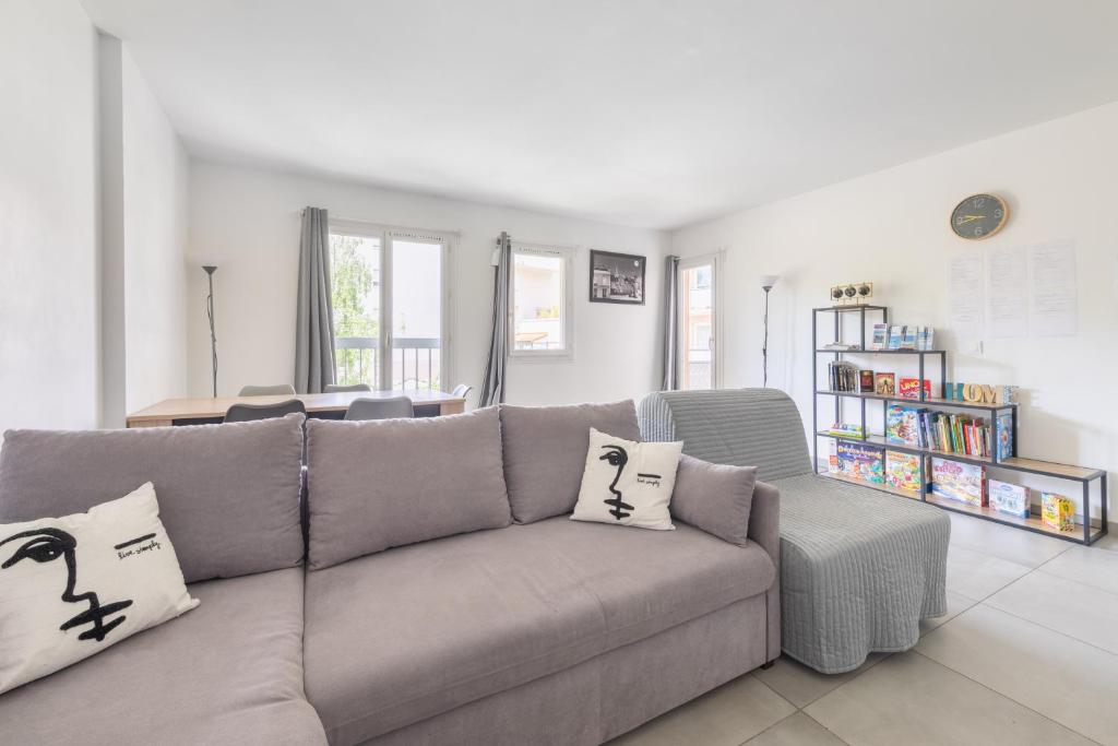 a living room with a gray couch with pillows at Appartement proche Disneyland & Paris - 20 minutes - proche gare RER in Noisiel