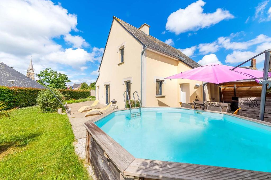 une piscine devant une maison avec un parasol rose dans l'établissement L'Escapade, grande maison, piscine et jardin, à Saint-Père