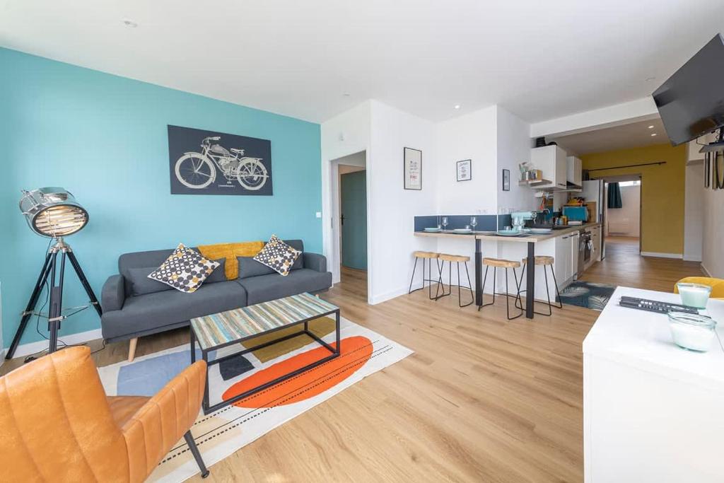 a living room with a couch and a kitchen at Le Green, appartement rénové, 4 chambres et jardin in Saint-Jacques-de-la-Lande