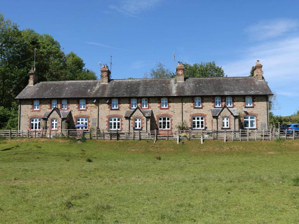 a large brick building on a grass field at 3 Railway Cottages in Long Marton