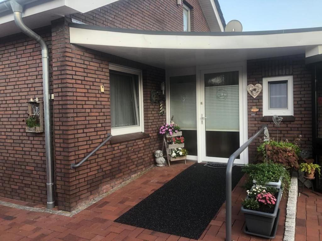 a brick house with a front porch with flowers at Ferienwohnung "Fehn-Moor" 95156 in Rhauderfehn