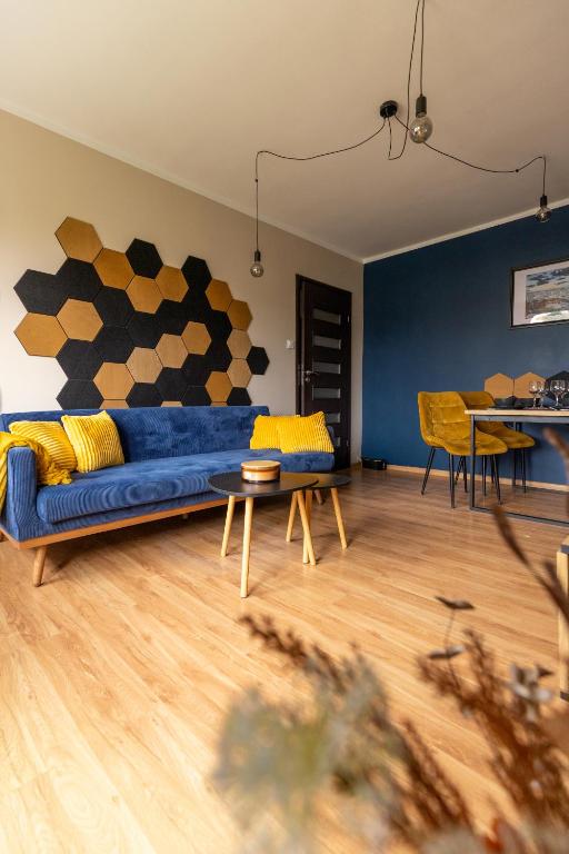 a living room with a blue couch and a table at Hexagon Studio Comfort in Gdańsk