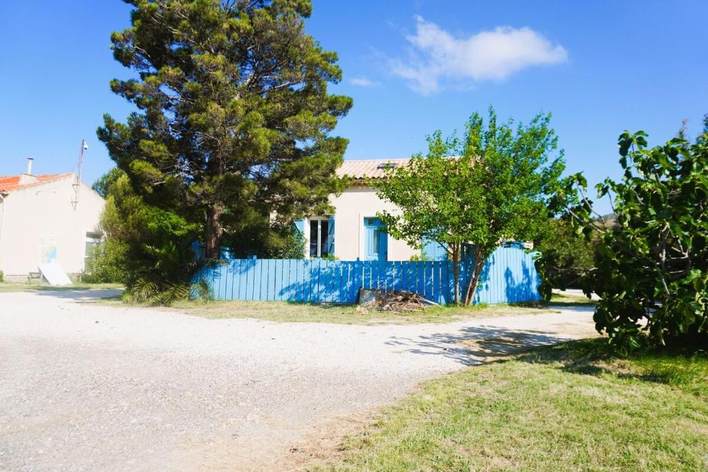une maison blanche avec une clôture bleue et des arbres dans l'établissement La Maison du Saunier entre mer et garrigue, à Lapalme