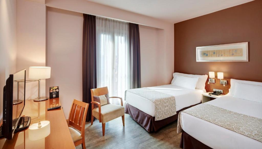 Una habitación de hotel con dos camas y un televisor. en Sercotel Alcalá 611, en Madrid