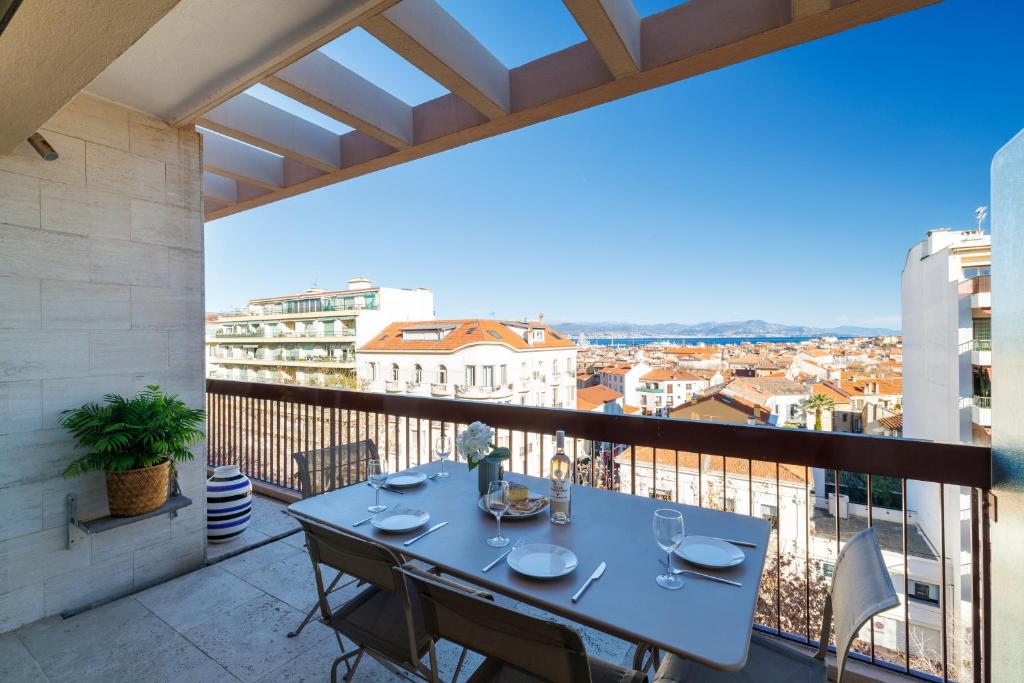 une table sur un balcon avec vue sur une ville dans l'établissement Skyline 2-bedroom flat with Epic Views - Roi Chevalier, à Antibes