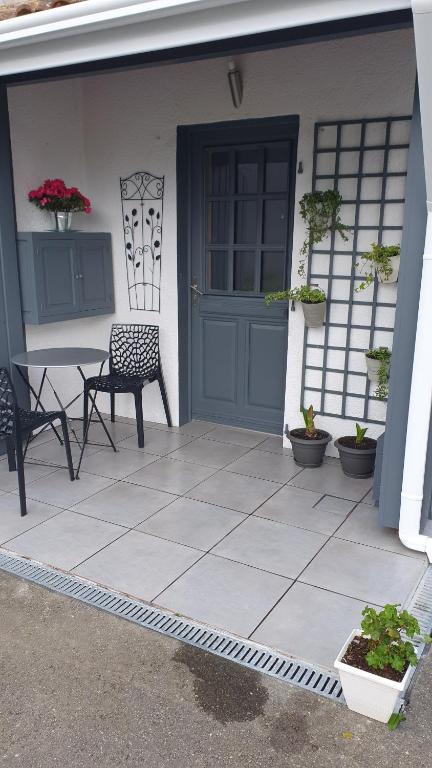 une terrasse avec une porte bleue, une table et une chaise dans l'établissement STUDIO L'HORIZON, à Doazit