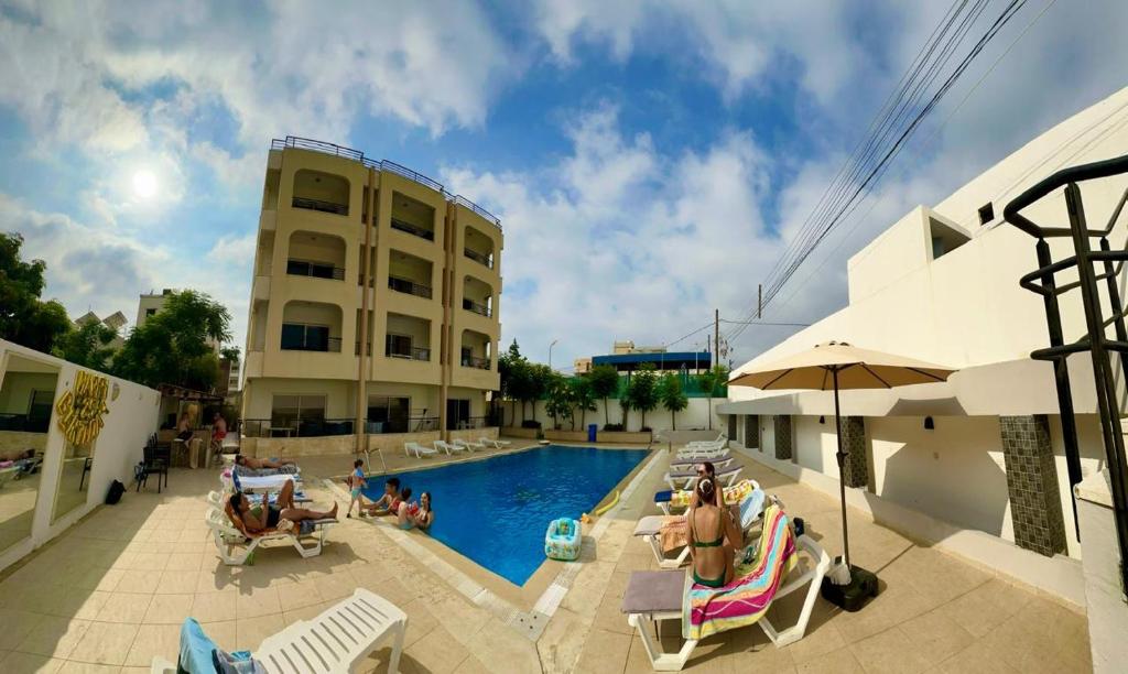 a swimming pool next to a building with people sitting around it at Etoile DE Mer in Al ‘Ayn