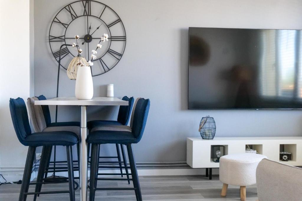 une salle à manger avec une table, des chaises et une horloge dans l'établissement Maison à étage avec cour et garage les Sables - 4 personnes, à Les Sables-dʼOlonne