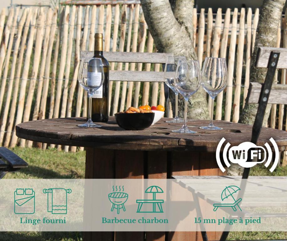 - une table avec 2 verres à vin et un bol de fruits dans l'établissement Maison La Rose des Vents, avec WIFI, proche plage et commerces, à Brem-sur-Mer