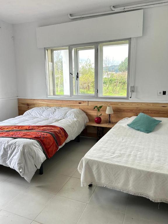 two beds in a room with two windows at Casa Sanuk in Poio