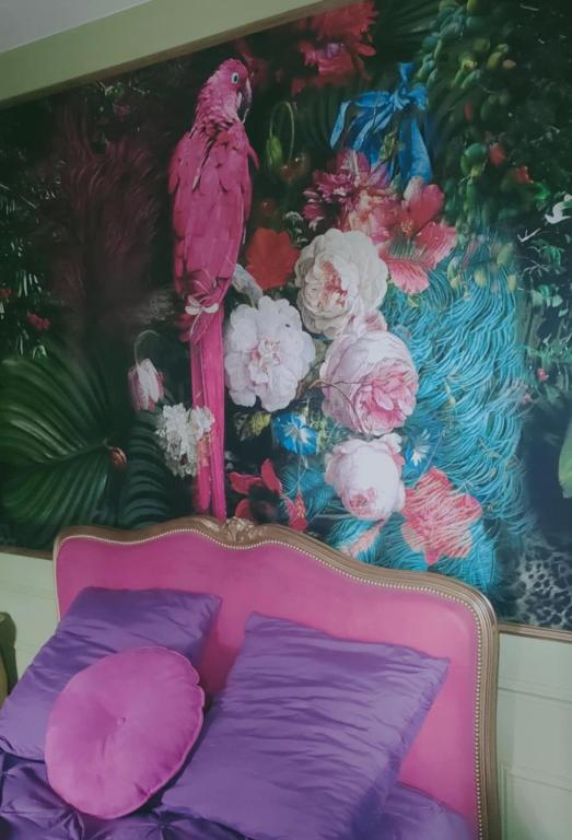 un lit rose avec des oreillers violets et une peinture d'un oiseau dans l'établissement maison de charme, à La Celle-sous-Gouzon