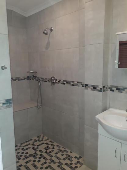a white bathroom with a shower and a sink at Muthaiga Stays - Studio Venue in Durban