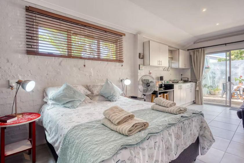 Muthaiga Stays - Studio Venue في ديربان: غرفة نوم بها سرير كبير مع مناشف عليه