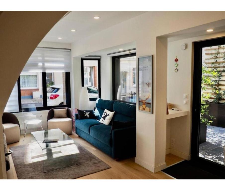 ein Wohnzimmer mit einem blauen Sofa und einem Tisch in der Unterkunft Centre ville Le Touquet, Villa familiale Villa familiale 3 grandes chambres, terrasse, intimité et Confort in Le Touquet-Paris-Plage