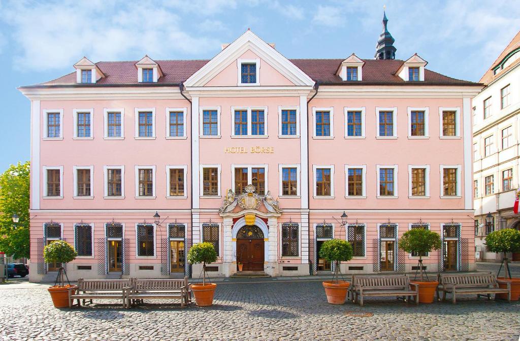 a large pink building with benches in front of it at Hotel Börse in Görlitz