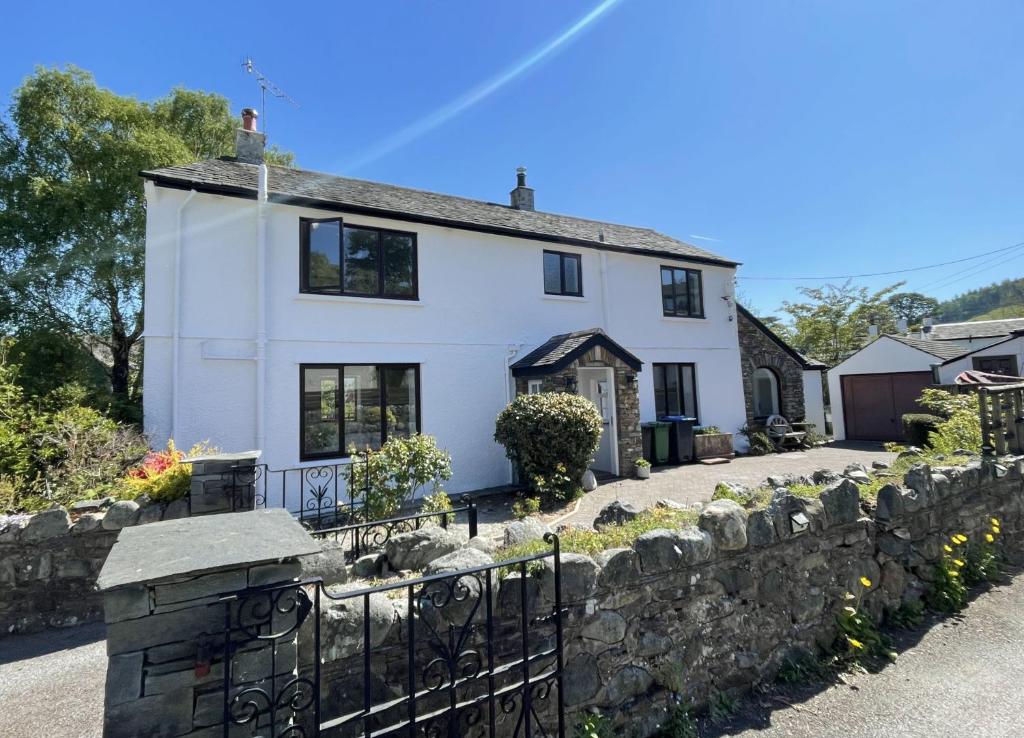 a white house with a stone wall at Mill House in Braithwaite