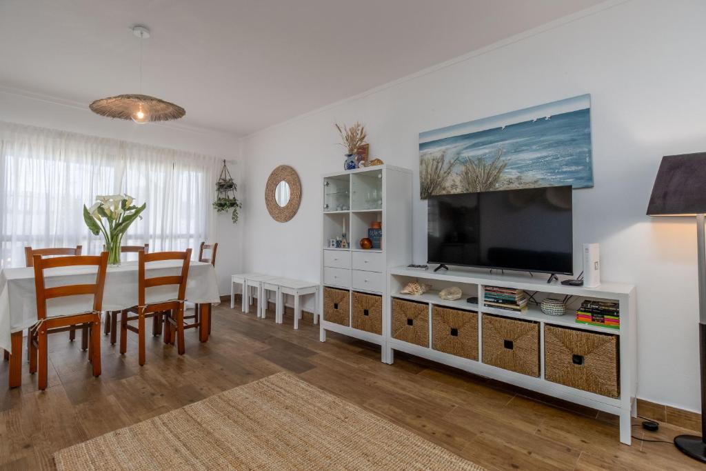 a living room with a television and a dining room table at Nest by the Lagoa, Carvalhal in Carvalhal