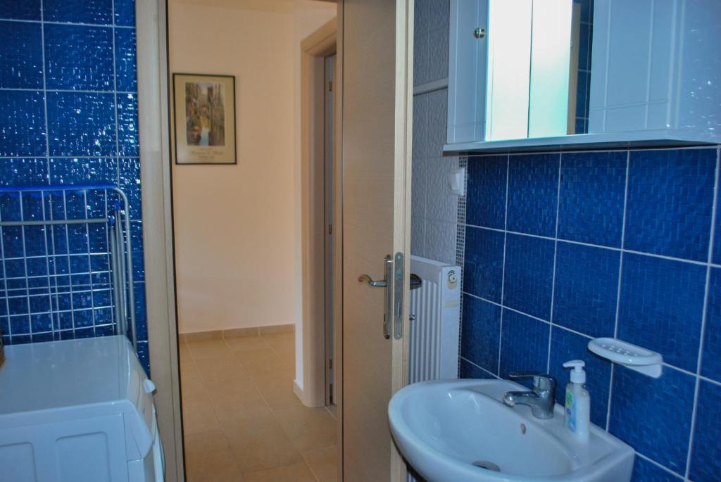 a blue tiled bathroom with a sink and a shower at Canal Luxury Apartments in Nea Potidaea