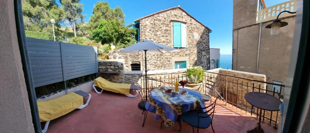 ein Balkon mit Tisch und Stühlen und einem Sonnenschirm in der Unterkunft Maison T3, quartier des peintres, calme et standing, patio privé, clim et wifi in Collioure