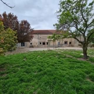 a building with a tree in the middle of a field at La ferme in Savigny