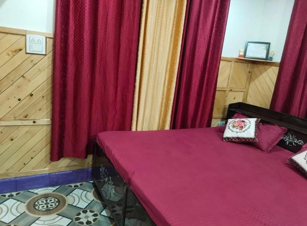 una stanza con un letto viola con tende rosse di Vaishnavi Homestay Yamunotri a Kharsālī