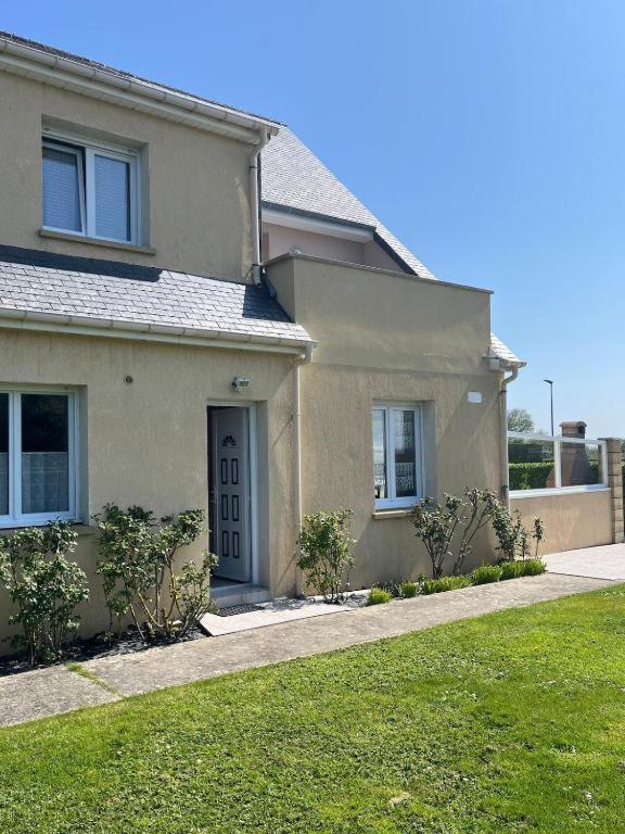 une maison avec une cour d'herbe devant elle dans l'établissement Gîtes de la Mouette Le Tourteau 5-6 pers, à Ravenoville