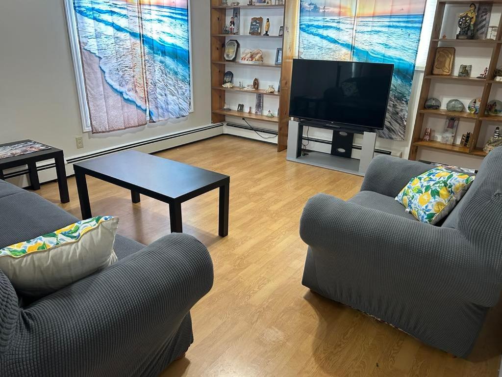 a living room with two couches and a tv at Whale Cove Suites in Digby