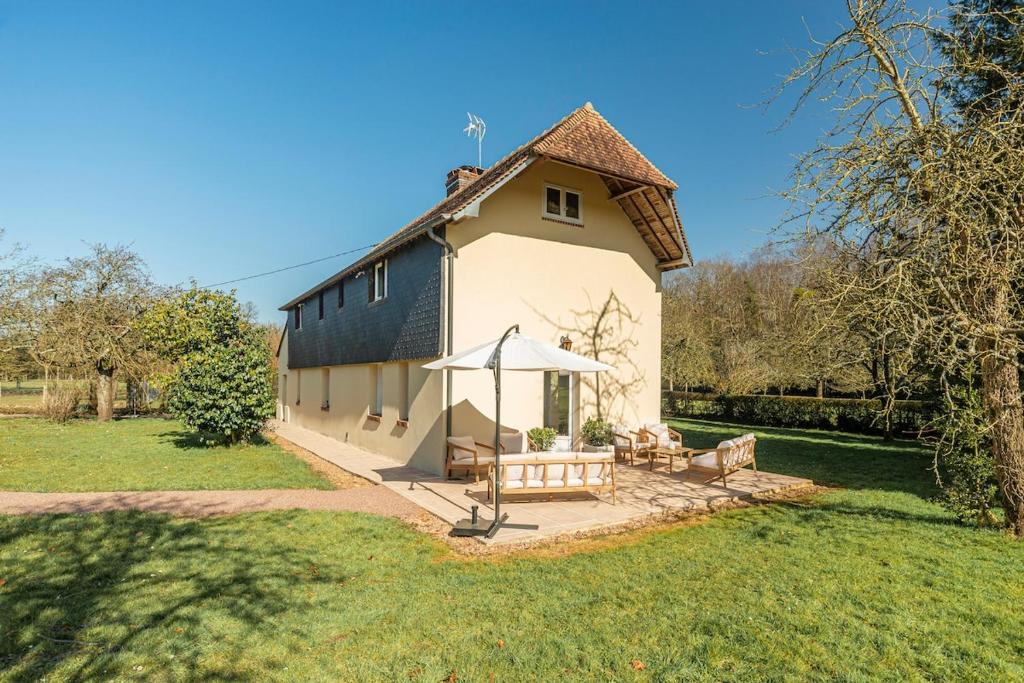 un petit bâtiment blanc avec une table et un parasol dans l'établissement Superbe maison de campagne aux portes de Deauville, à Pierrefitte-en-Auge